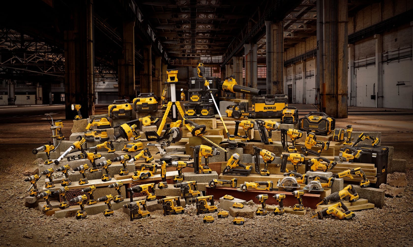 A large assortment of DEWALT yellow and black power tools and toolboxes displayed in an industrial warehouse setting.